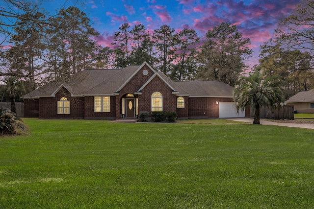 view of front of home with an attached garage, brick siding, a yard, and driveway