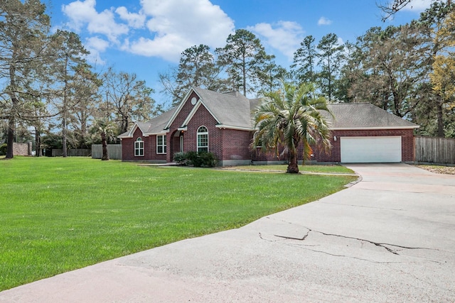 ranch-style house featuring a front yard, fence, an attached garage, concrete driveway, and brick siding