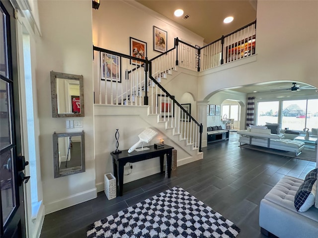 foyer with stairway, dark wood-style floors, arched walkways, and ceiling fan