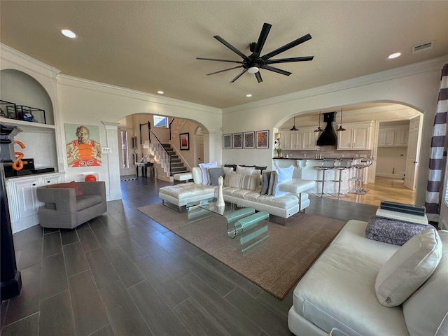 living room with wood finished floors, visible vents, arched walkways, and ceiling fan