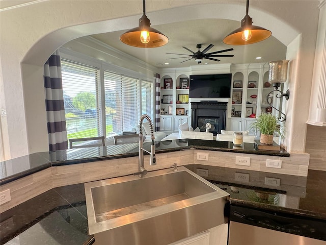 kitchen with a glass covered fireplace, built in shelves, a sink, stainless steel dishwasher, and a textured wall