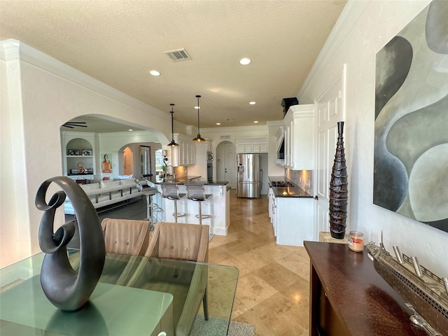 living area with visible vents, a textured ceiling, recessed lighting, arched walkways, and crown molding