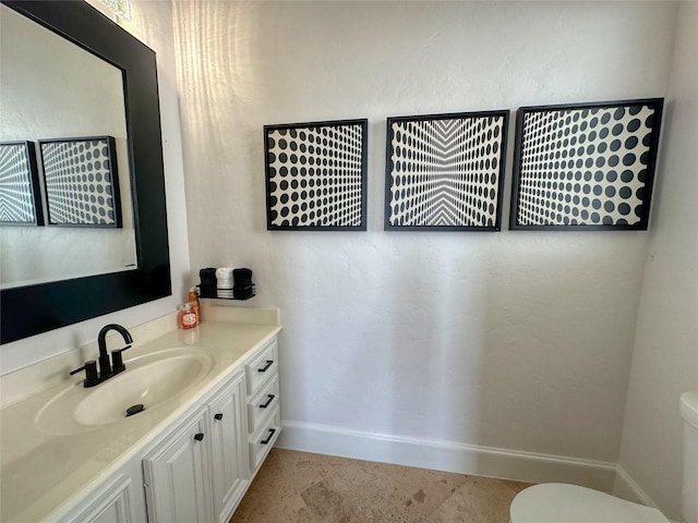 bathroom featuring toilet, vanity, and baseboards