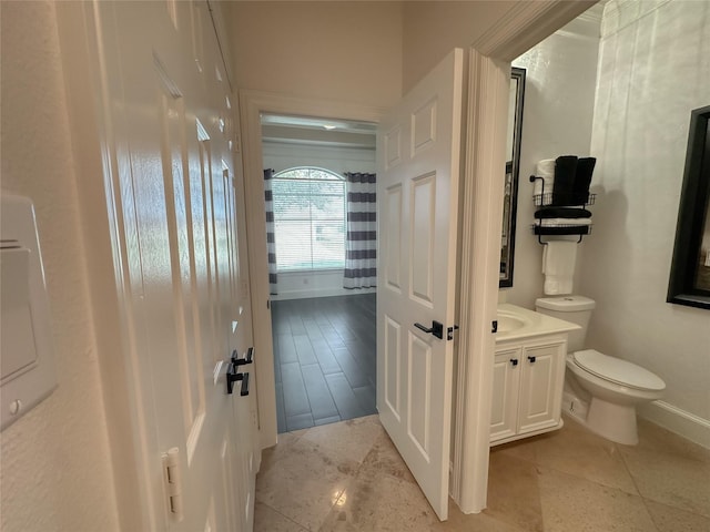 half bathroom with vanity, toilet, and baseboards