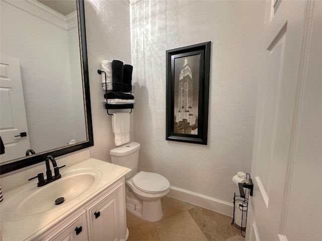 half bathroom with vanity, baseboards, ornamental molding, tile patterned flooring, and toilet