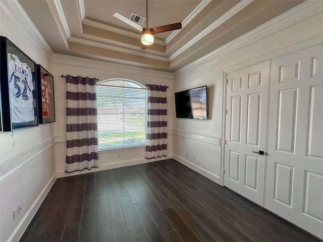 spare room with ceiling fan, crown molding, a tray ceiling, and dark wood-style flooring