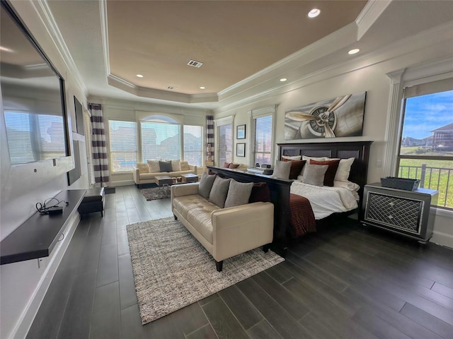 bedroom with a tray ceiling, multiple windows, ornamental molding, and dark wood-style flooring