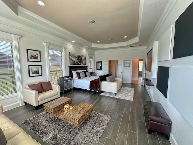 bedroom featuring visible vents, crown molding, baseboards, wood tiled floor, and a raised ceiling