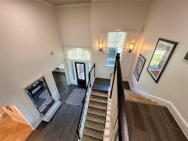 stairs featuring a high ceiling, wood finished floors, visible vents, and baseboards