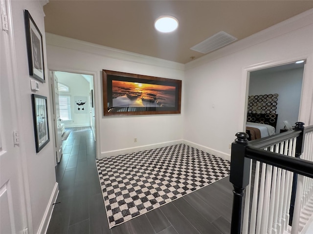 hallway with visible vents, baseboards, ornamental molding, an upstairs landing, and wood finished floors