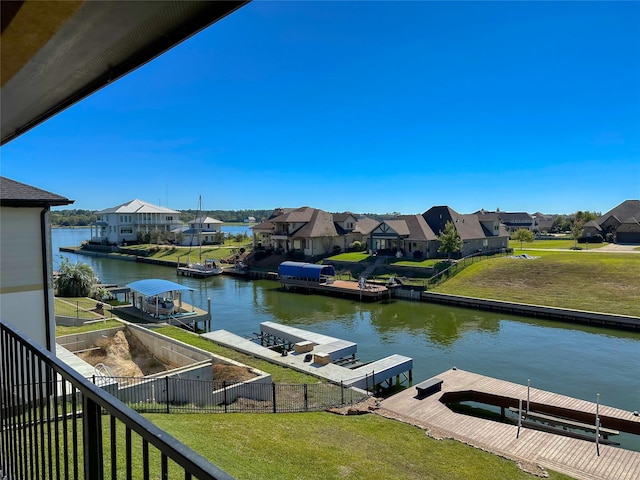 dock area with a residential view, fence, a lawn, and a water view