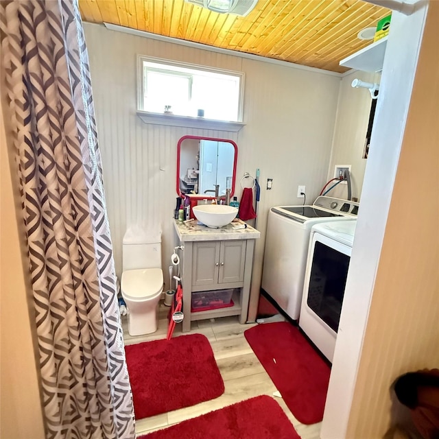 laundry area with laundry area, light wood-style flooring, separate washer and dryer, a sink, and wooden ceiling