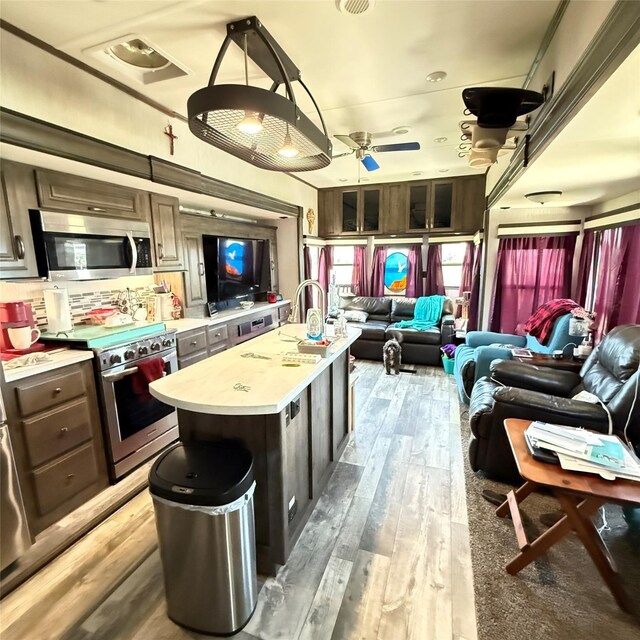 kitchen featuring light countertops, light wood-type flooring, open floor plan, and stainless steel appliances