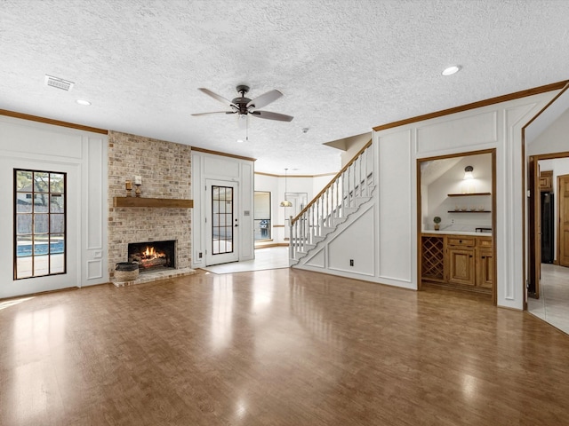 unfurnished living room featuring a decorative wall, visible vents, a ceiling fan, and wood finished floors