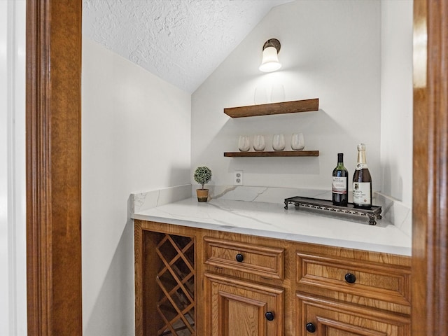 bar with lofted ceiling, a bar, and a textured ceiling