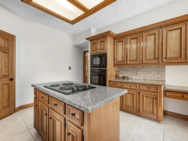 kitchen featuring light stone counters, light tile patterned floors, brown cabinets, black appliances, and tasteful backsplash