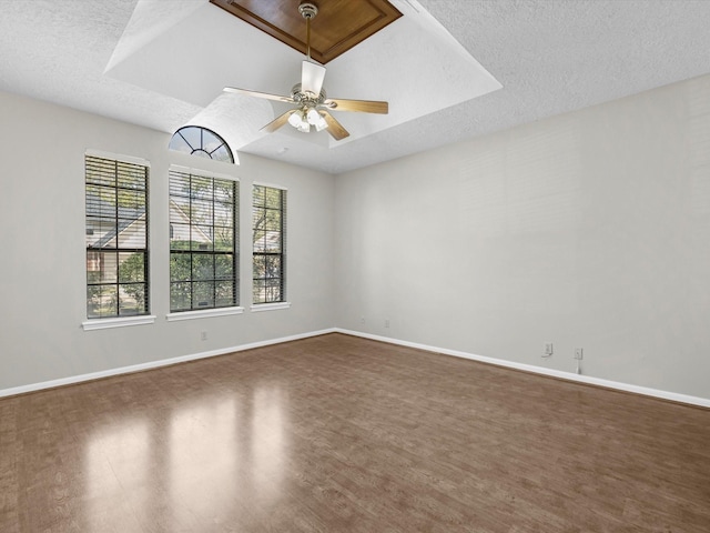 empty room featuring dark wood finished floors, a ceiling fan, baseboards, and a textured ceiling