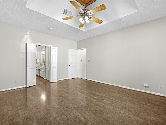 unfurnished bedroom featuring baseboards, visible vents, dark wood-type flooring, a textured ceiling, and connected bathroom