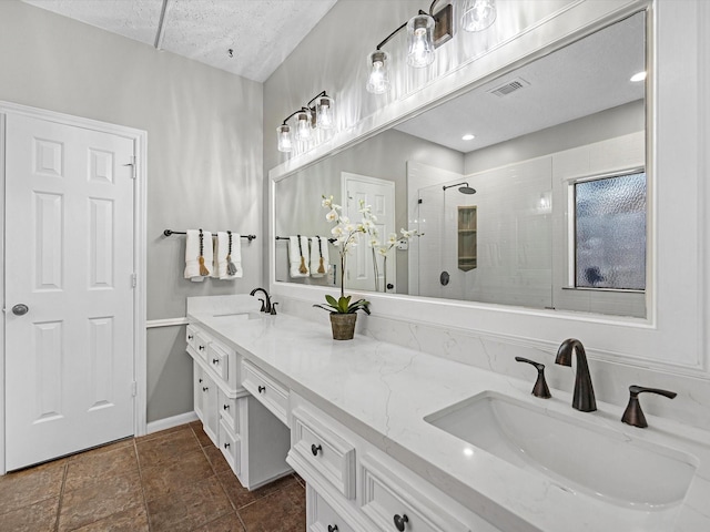 full bathroom featuring double vanity, visible vents, tiled shower, and a sink