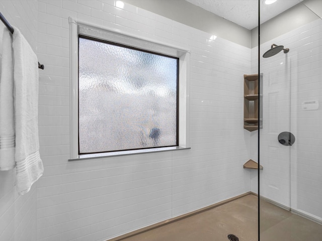 bathroom with a tile shower and a textured ceiling