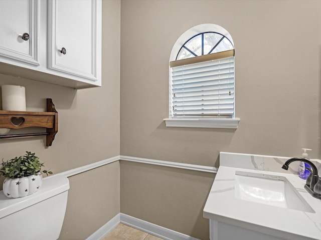 bathroom featuring toilet, vanity, and baseboards