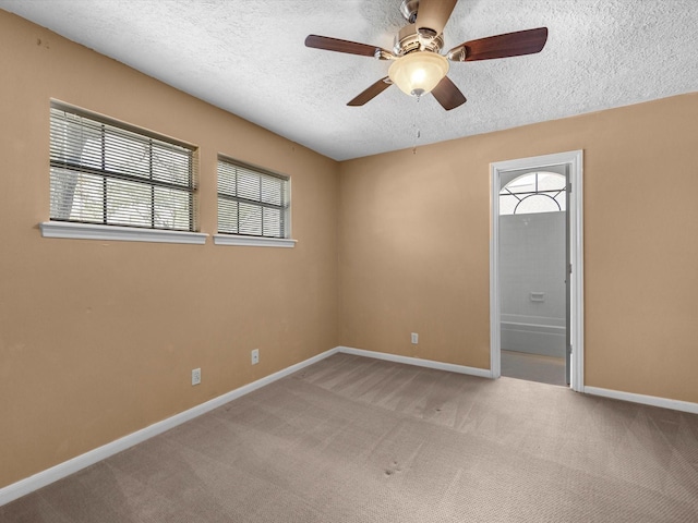 carpeted spare room with a ceiling fan, baseboards, and a textured ceiling