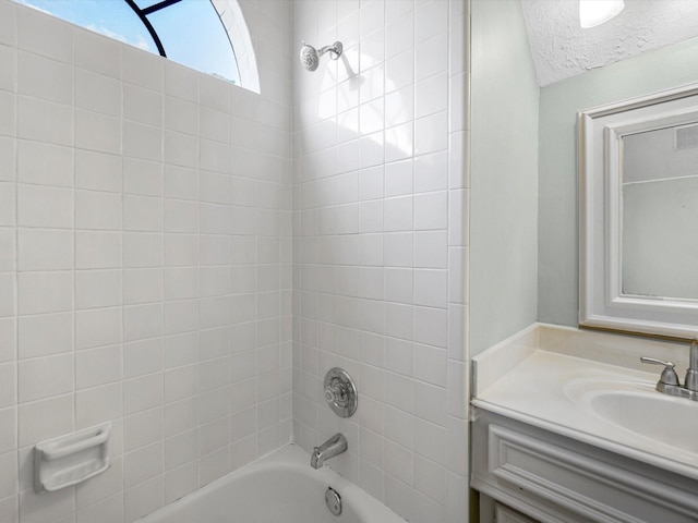 bathroom featuring a textured ceiling, washtub / shower combination, and vanity