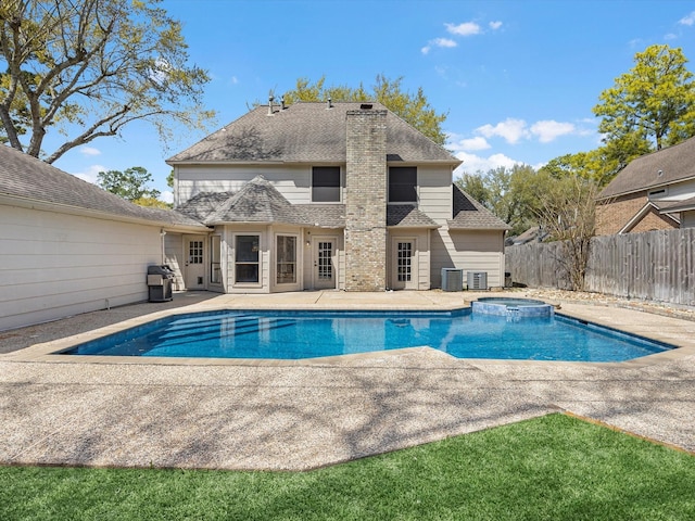 view of pool with a patio area, cooling unit, a pool with connected hot tub, and fence