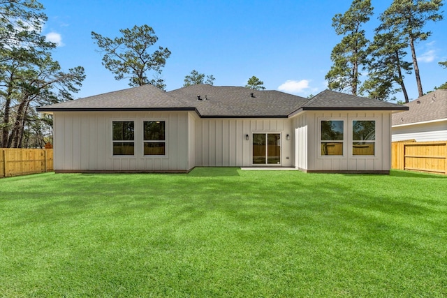 rear view of property with a yard, fence, and roof with shingles