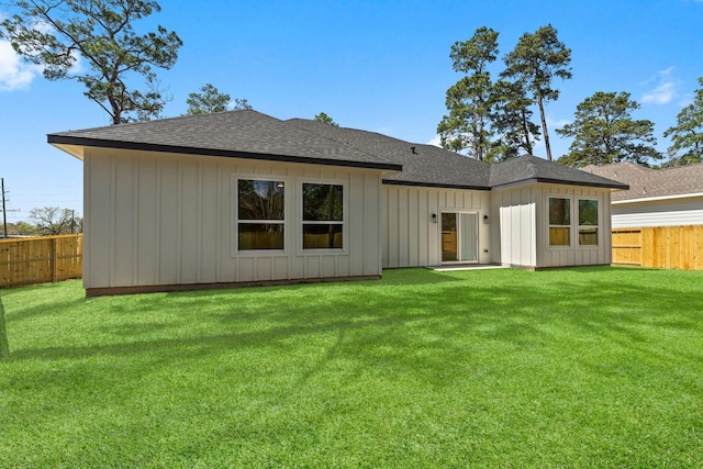 back of property featuring a yard, board and batten siding, a shingled roof, and fence