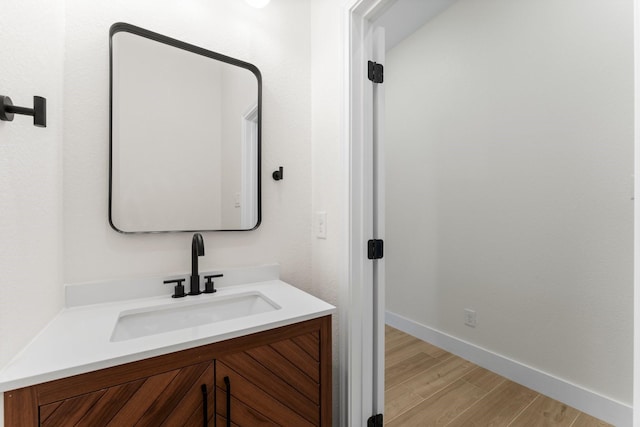 bathroom featuring baseboards, wood finished floors, and vanity