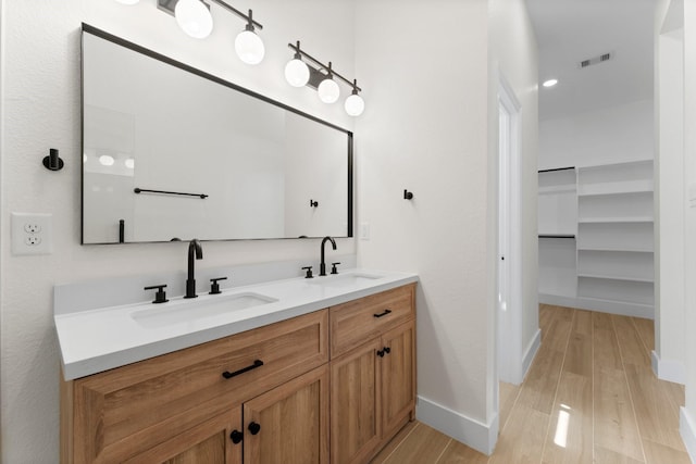 full bathroom featuring double vanity, visible vents, wood finished floors, and a sink