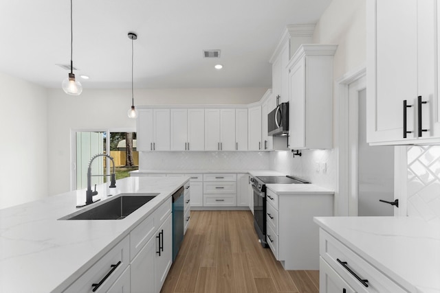 kitchen with pendant lighting, a sink, backsplash, white cabinetry, and stainless steel appliances