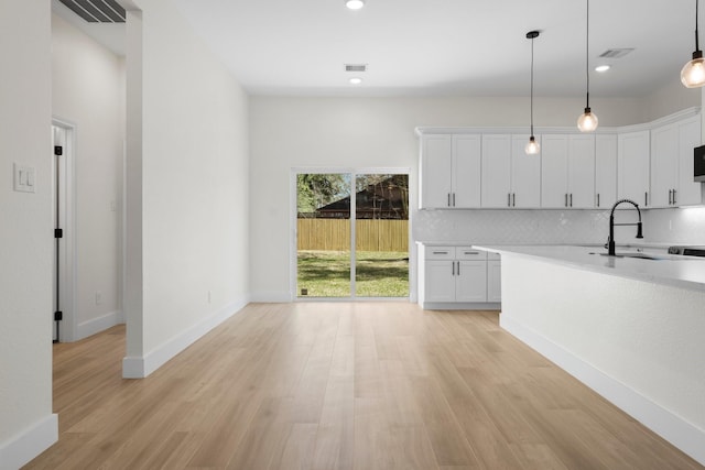 kitchen with visible vents, light wood finished floors, backsplash, and light countertops