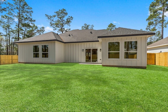 back of house featuring a yard, board and batten siding, roof with shingles, and a fenced backyard