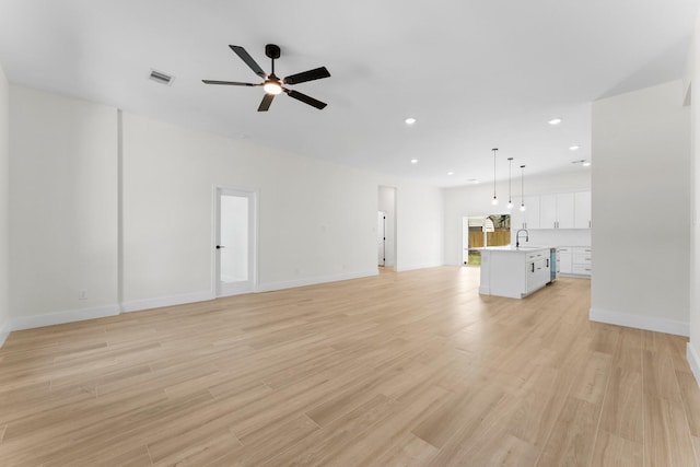 unfurnished living room featuring a sink, visible vents, light wood-style flooring, and ceiling fan