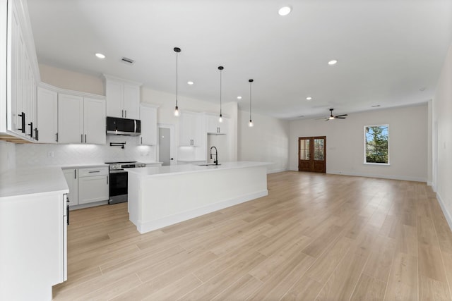 kitchen with visible vents, a sink, backsplash, appliances with stainless steel finishes, and ceiling fan