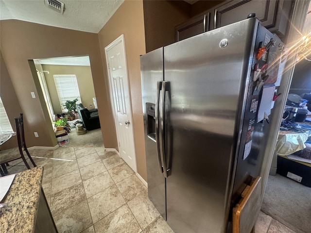 kitchen featuring visible vents, light countertops, lofted ceiling, stainless steel fridge, and a textured ceiling