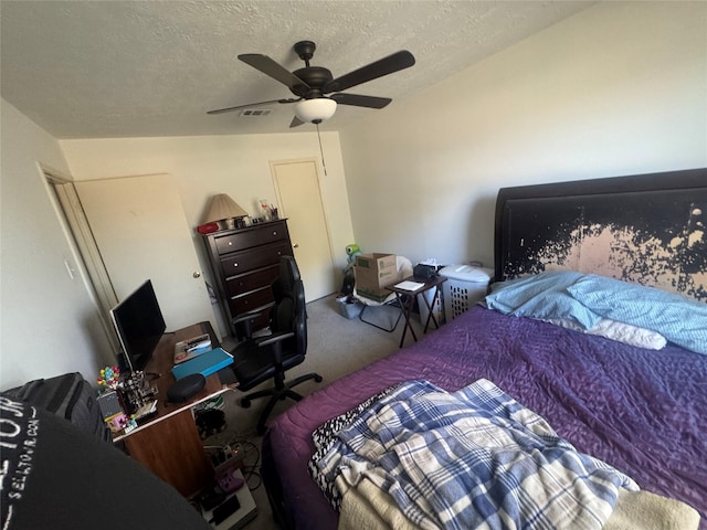 carpeted bedroom with visible vents, a textured ceiling, and ceiling fan