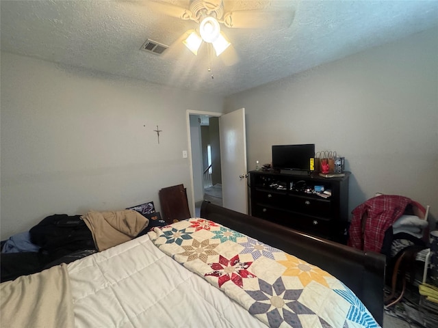 bedroom featuring ceiling fan, visible vents, and a textured ceiling