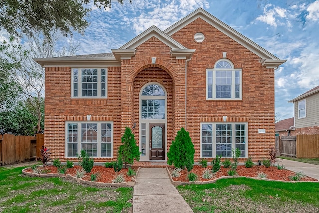 traditional-style home featuring brick siding and fence