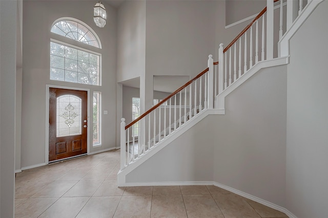 entryway with stairs, tile patterned floors, a high ceiling, and baseboards