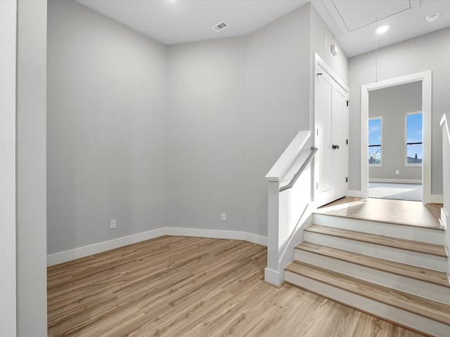 staircase with visible vents, baseboards, attic access, and wood finished floors