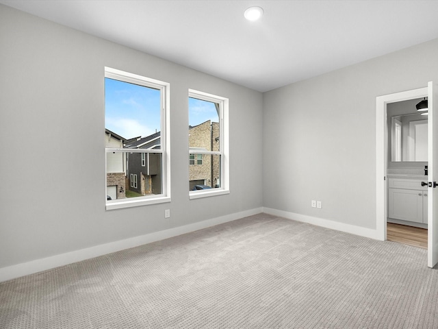 spare room with light carpet and baseboards