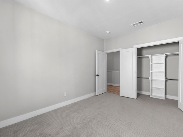 unfurnished bedroom with light colored carpet, visible vents, a closet, and baseboards