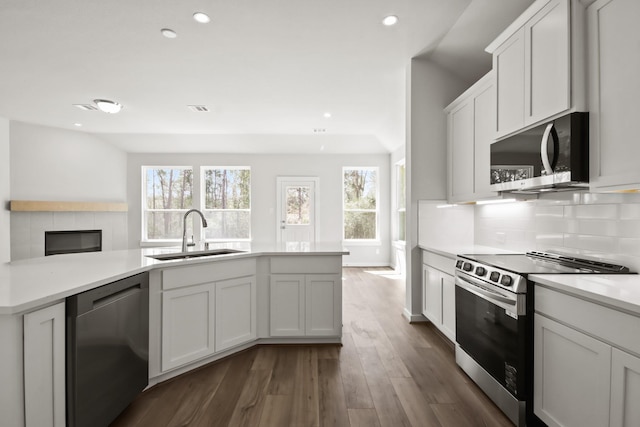 kitchen with dark wood-style floors, a sink, light countertops, appliances with stainless steel finishes, and tasteful backsplash