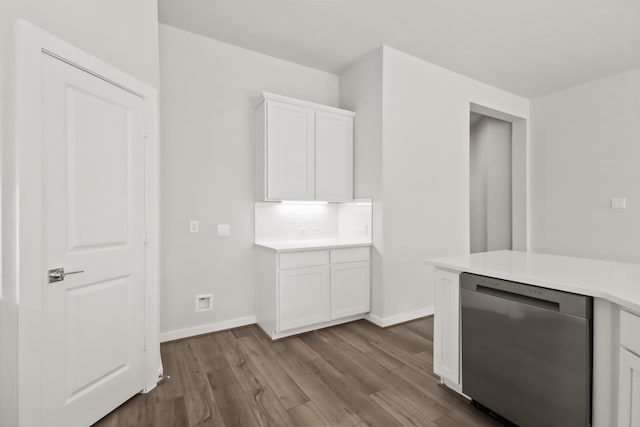 kitchen with wood finished floors, white cabinets, light countertops, baseboards, and dishwasher