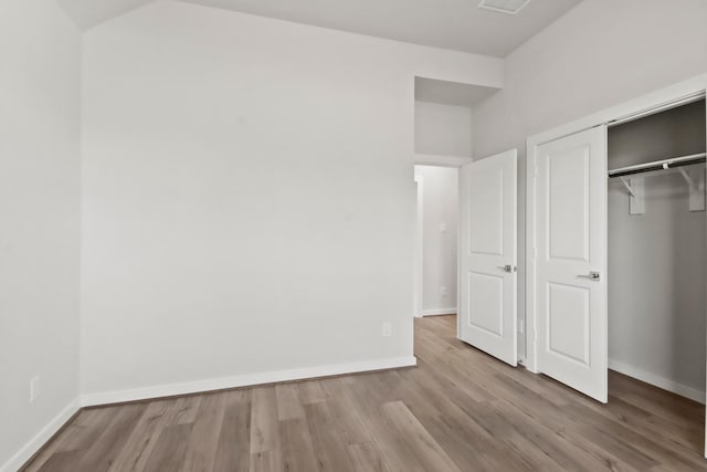 unfurnished bedroom with wood finished floors, baseboards, and a closet