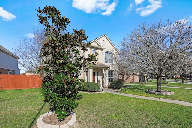 traditional-style home featuring brick siding, a front yard, and fence