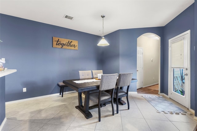 tiled dining area featuring visible vents, arched walkways, and baseboards